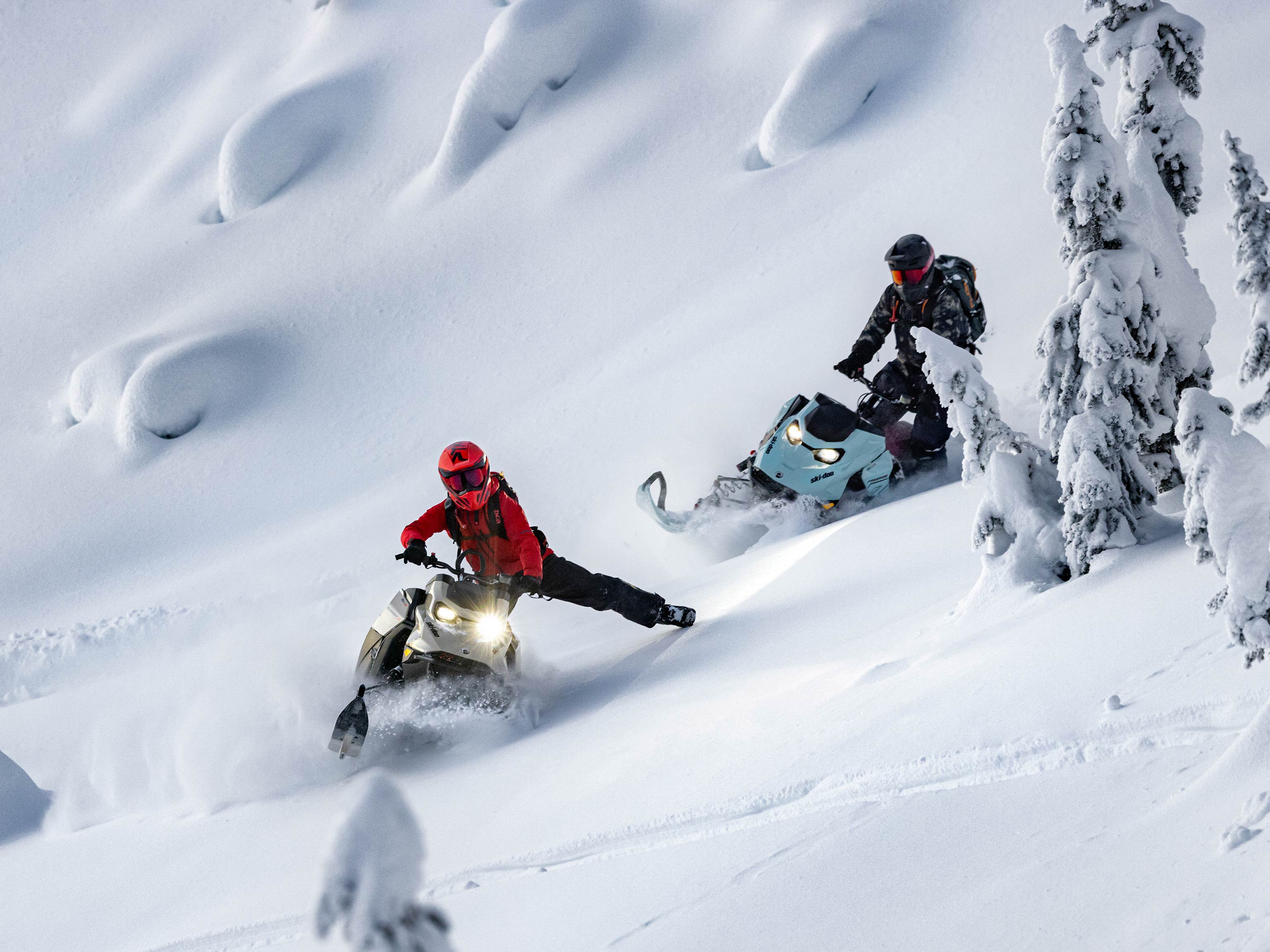 Kaksi kuljettajaa ajaa Ski-Doo syvän lumen moottorikelkkaa vuoristossa