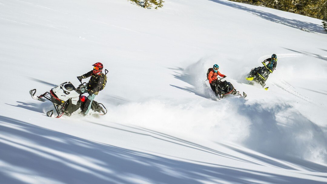 Three snowmobilers riding their Ski-Doo in deep snow