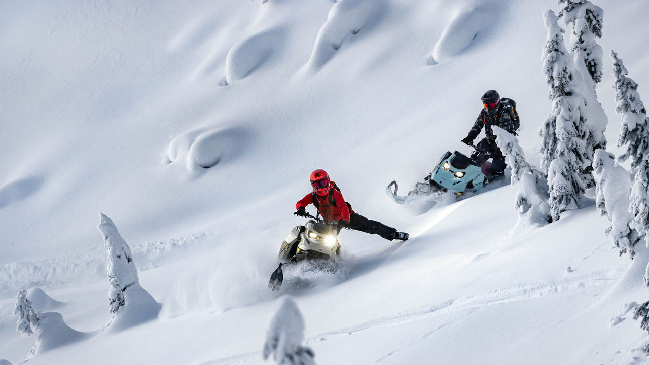 山でSki-Doo Deep Snowスノーモービルに乗っている2人