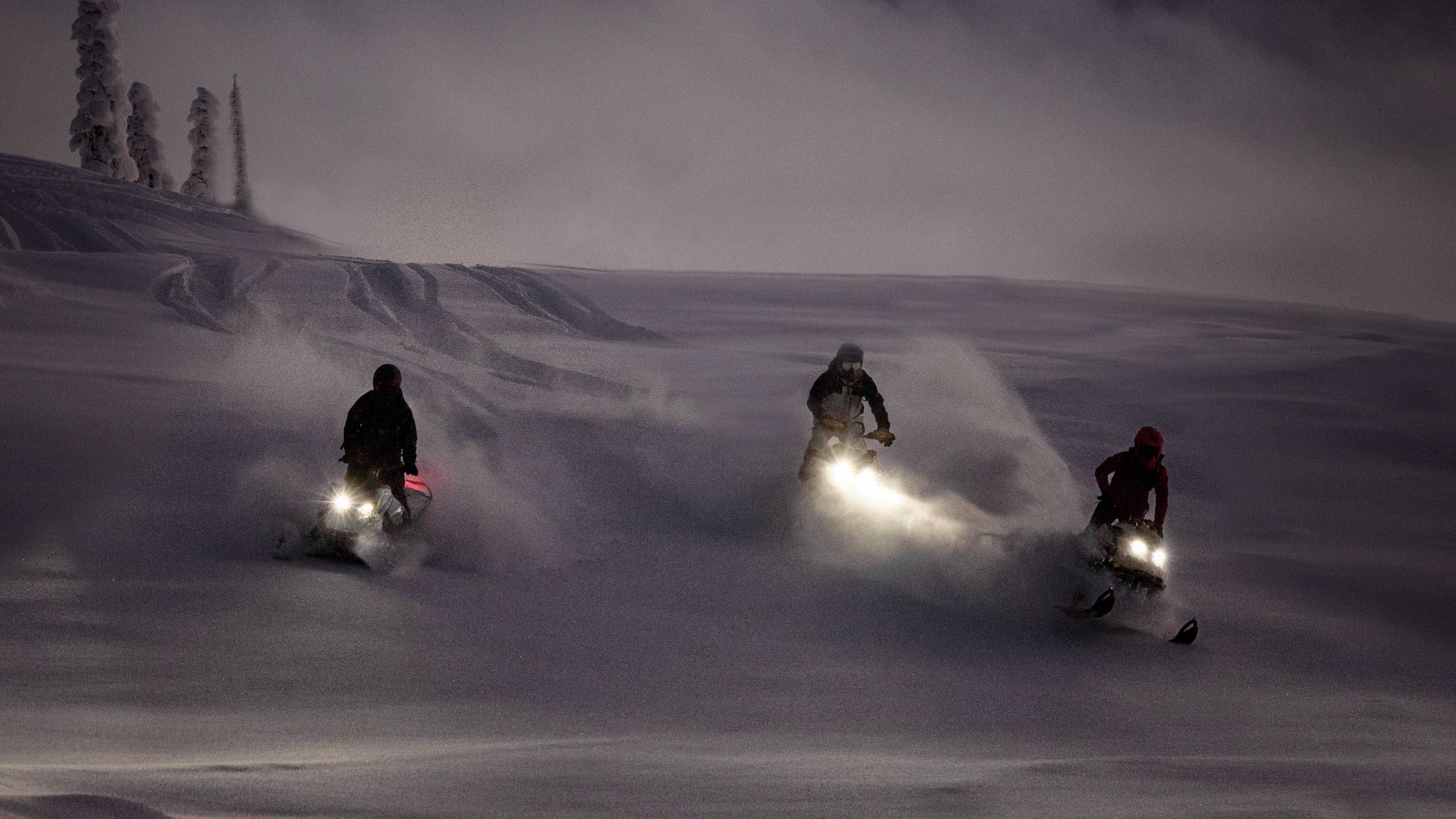 Three Ski-Doo snowmobilers in deep snow