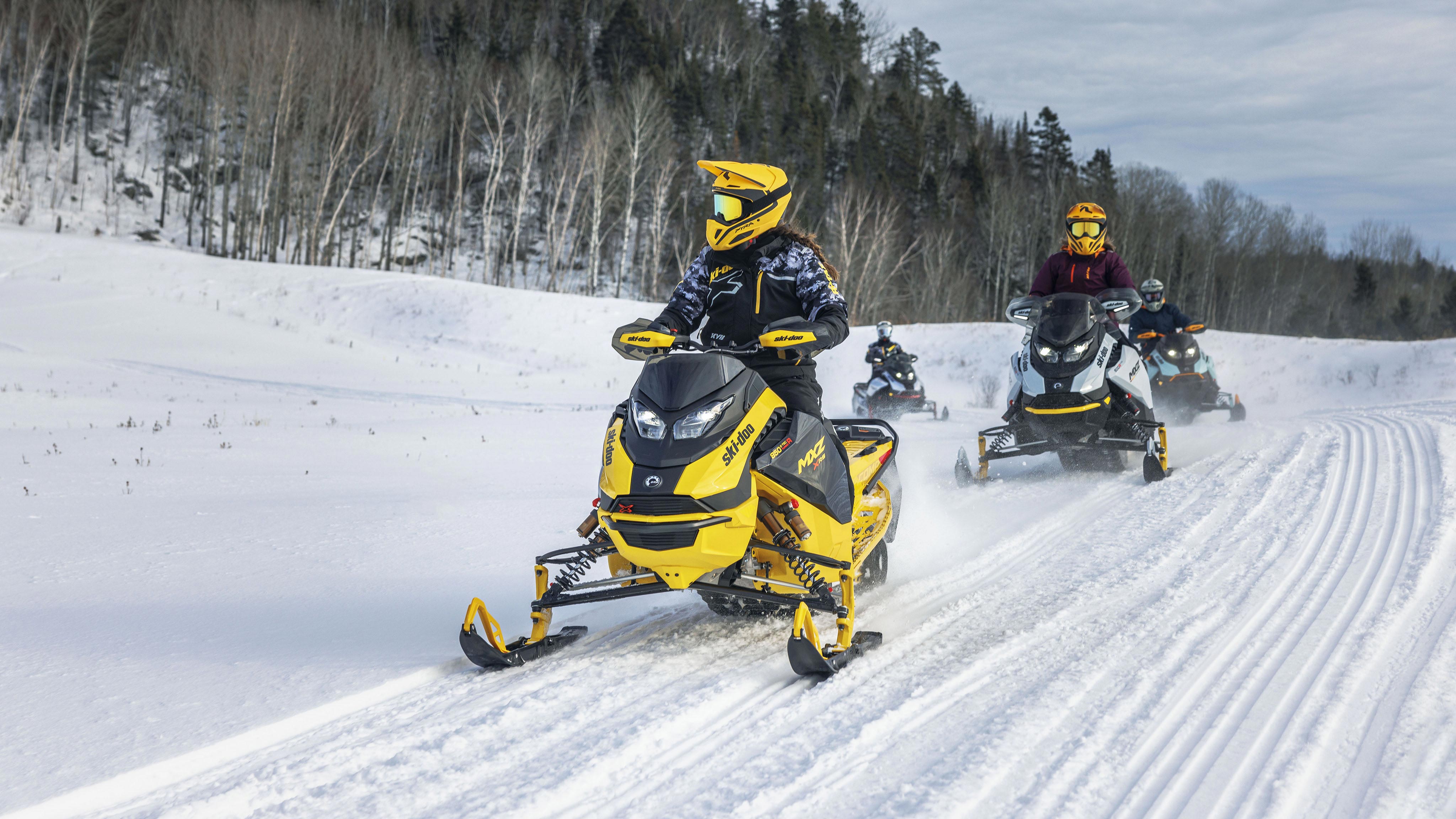Quatre motoneigistes sur leur Ski-Doo dans un sentier