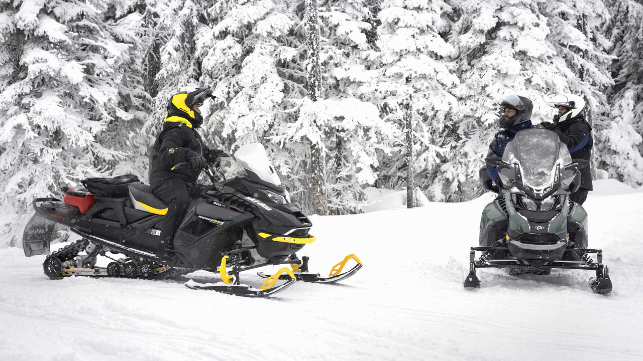 Three riders having a chat next to their sleds in trail