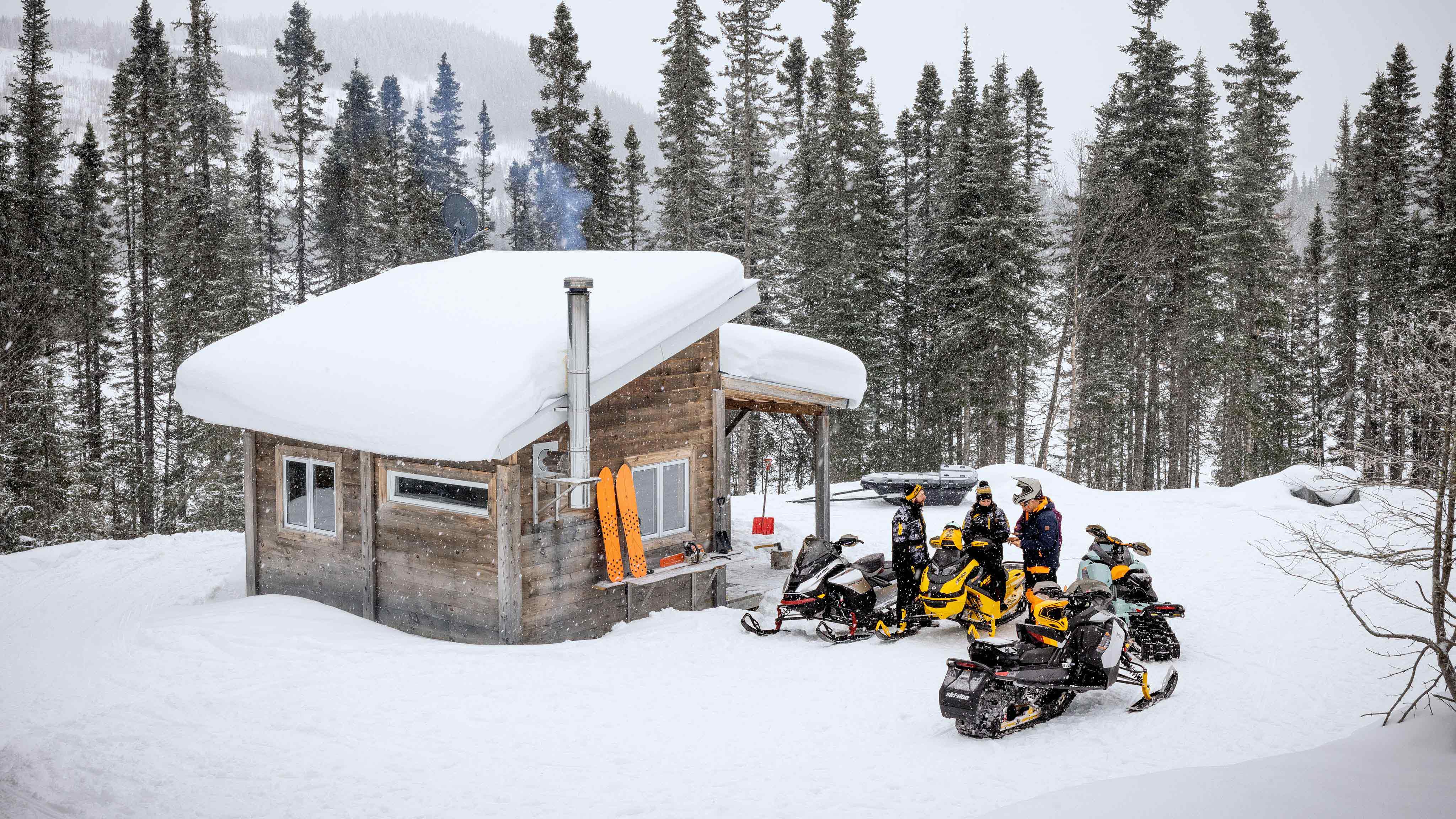 Group of snowmobile riders next to a small cottage