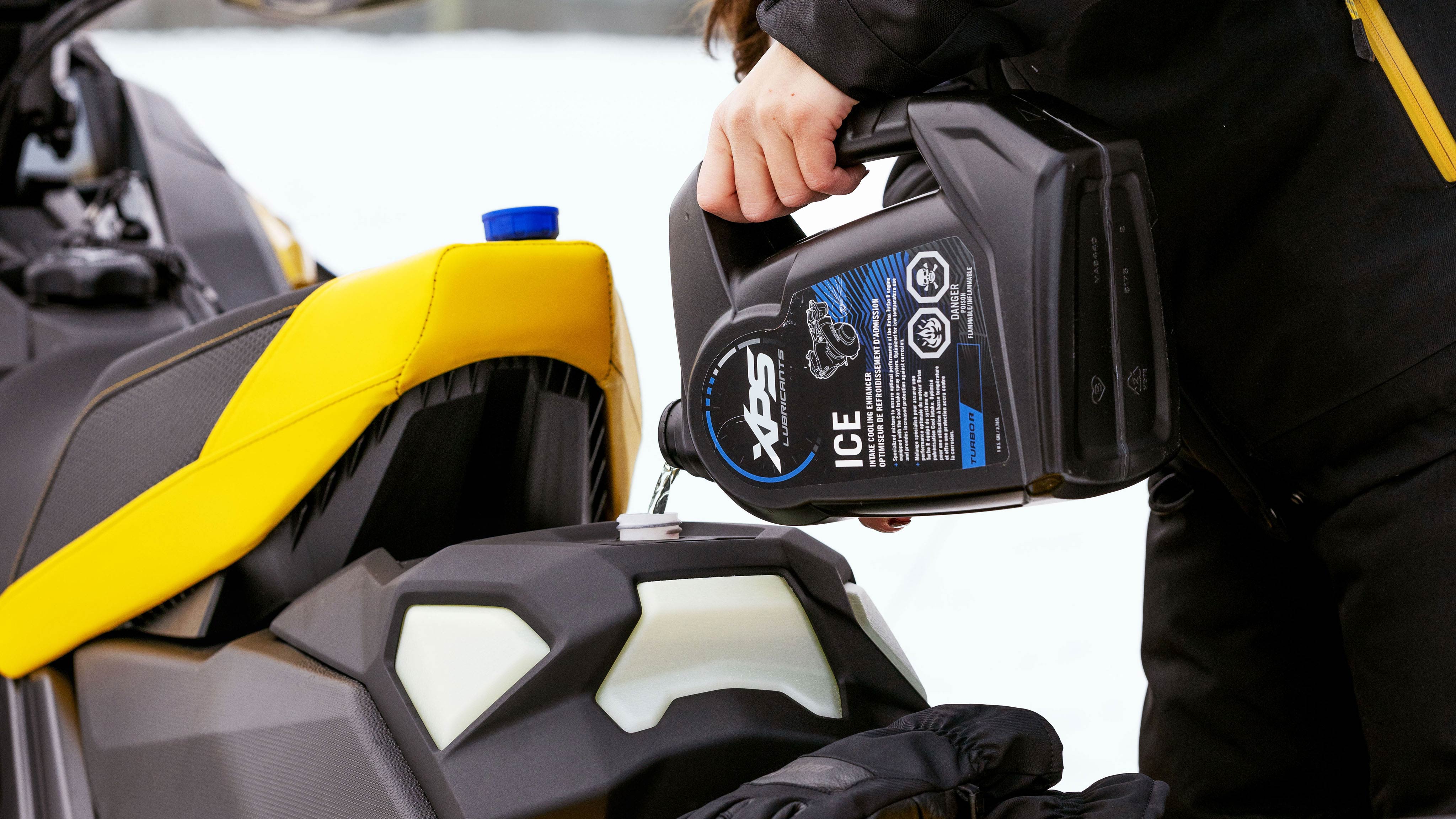 Person adding XPS ICE fluid to a Ski-Doo MXZ X-RS Competition package