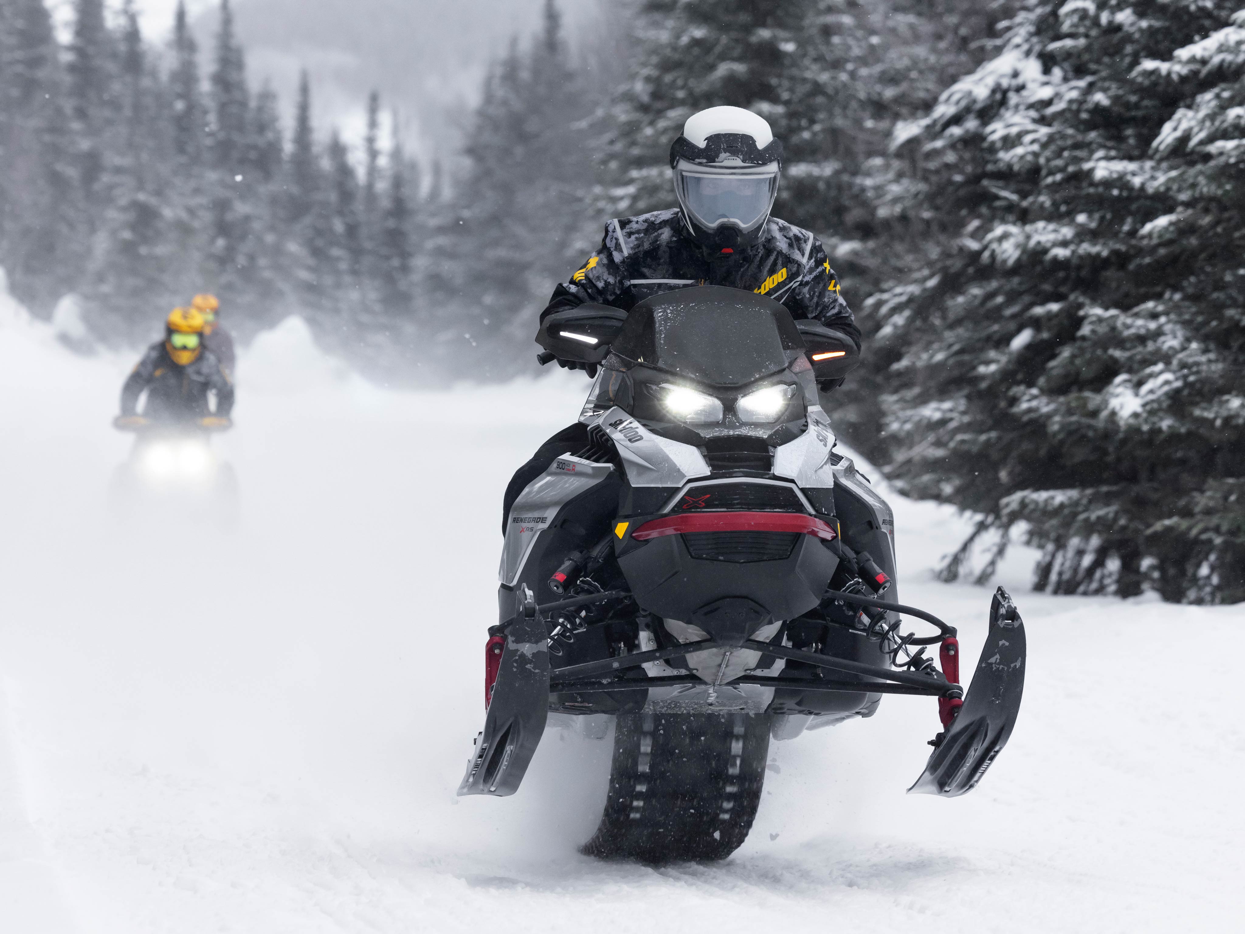 Man on Ski-Doo Renegade X-RS with other snowmobilers behind