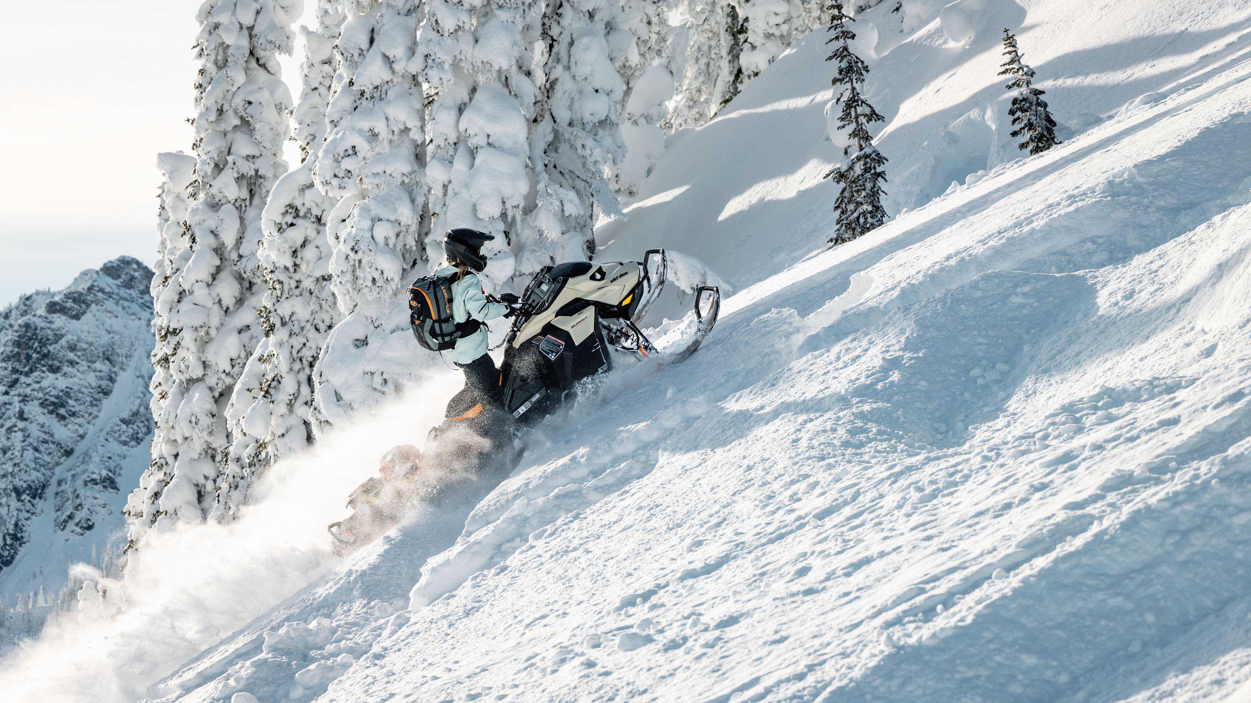 Femme conduisant une motoneige Ski-Doo Summit en montagne