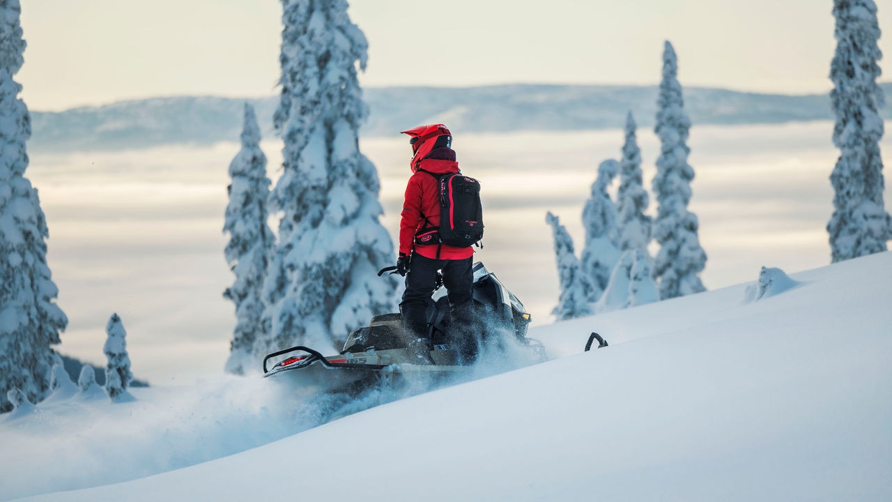 Rider standing on a Ski-Doo Summit at the top of a mountain