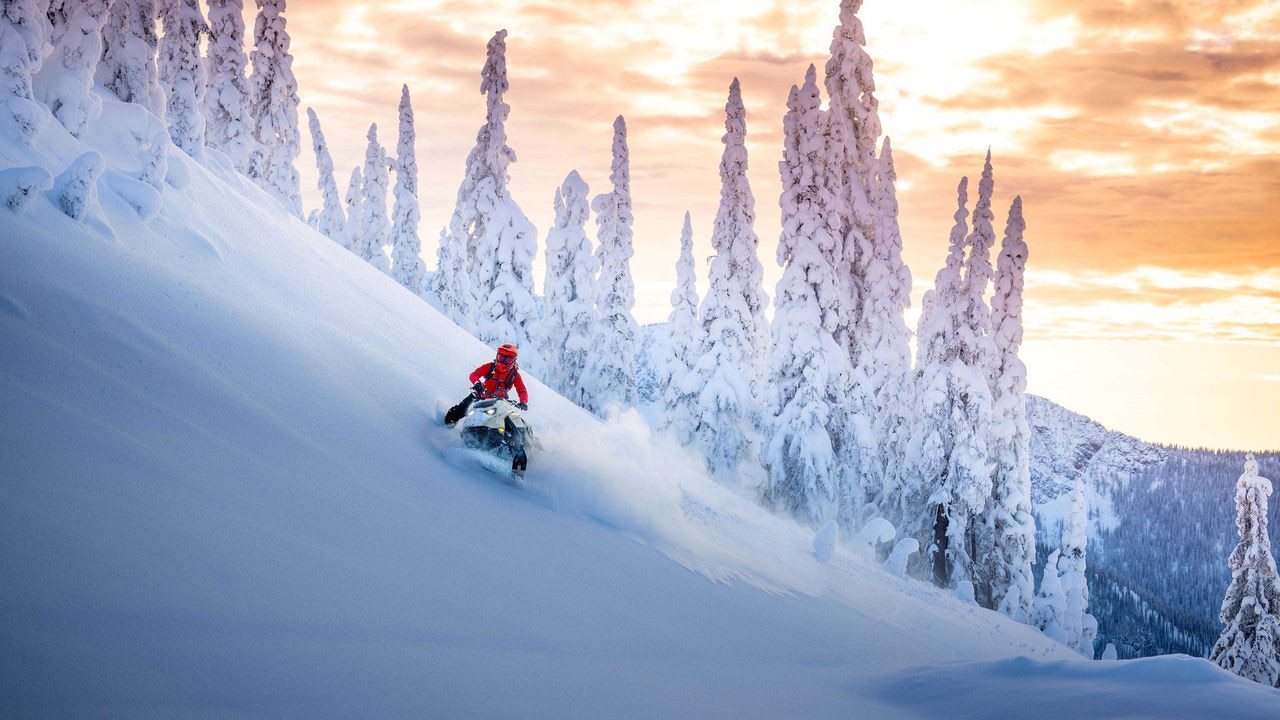 Homme conduisant une motoneige Ski-Doo Summit à flanc de montagne