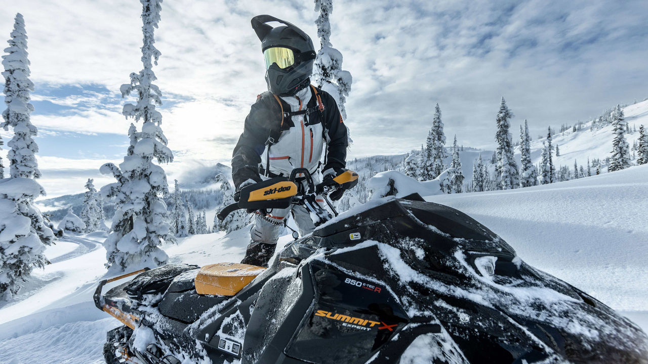 Homme faisant de la motoneige dans la neige profonde avec les vêtements Ski-Doo