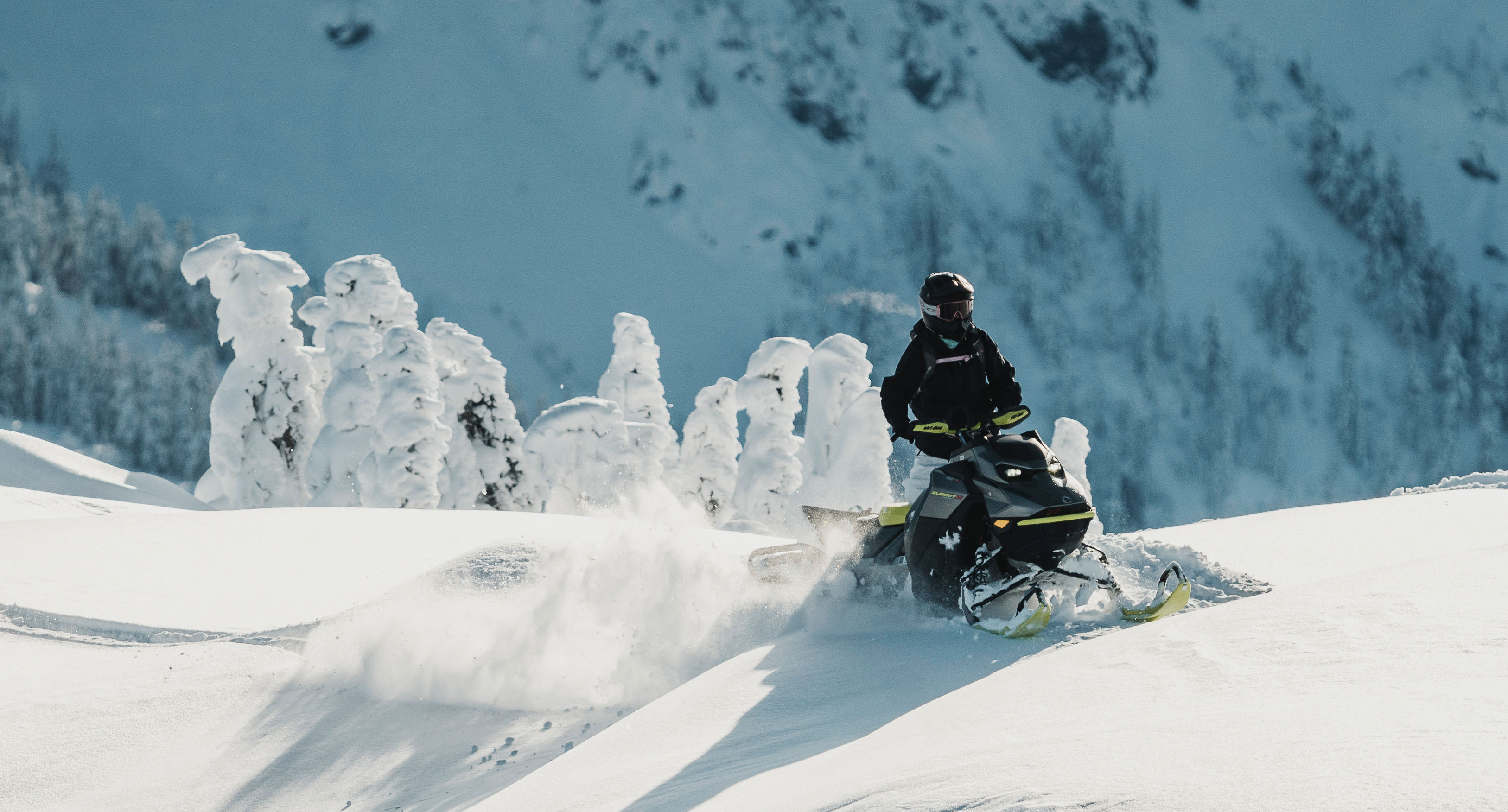 Jamie Anderson riding a Ski-Doo snowmobile on top of a mountain