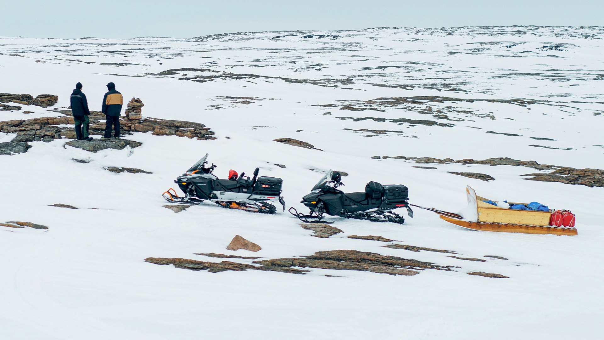 Kaksi miestä seisoo Ski-Doo-moottorikelkkansa vieressä Nunavutissa.