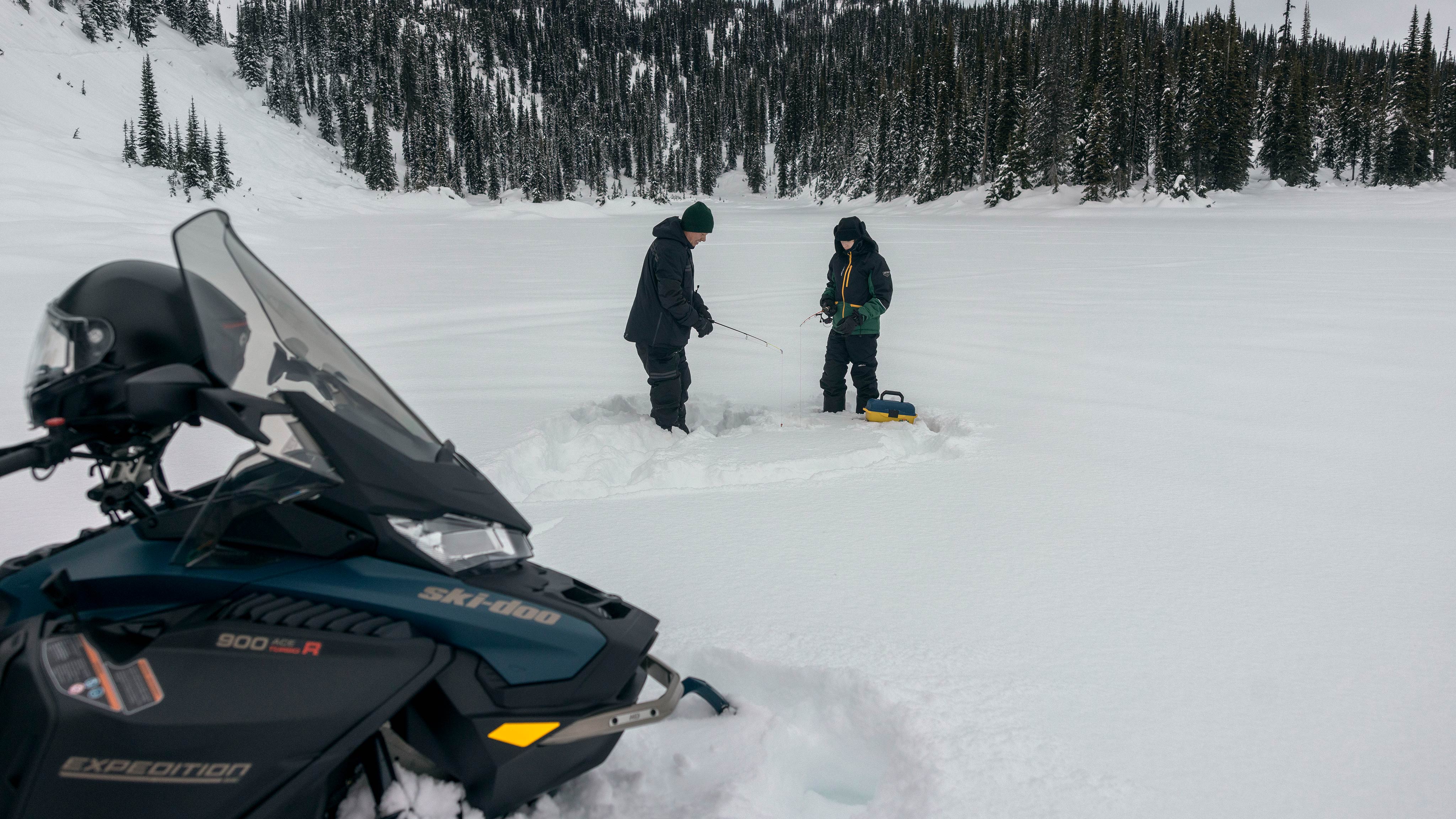Deux motoneigistes pêchant à côte d'un Ski-Doo multi-segment Expedition