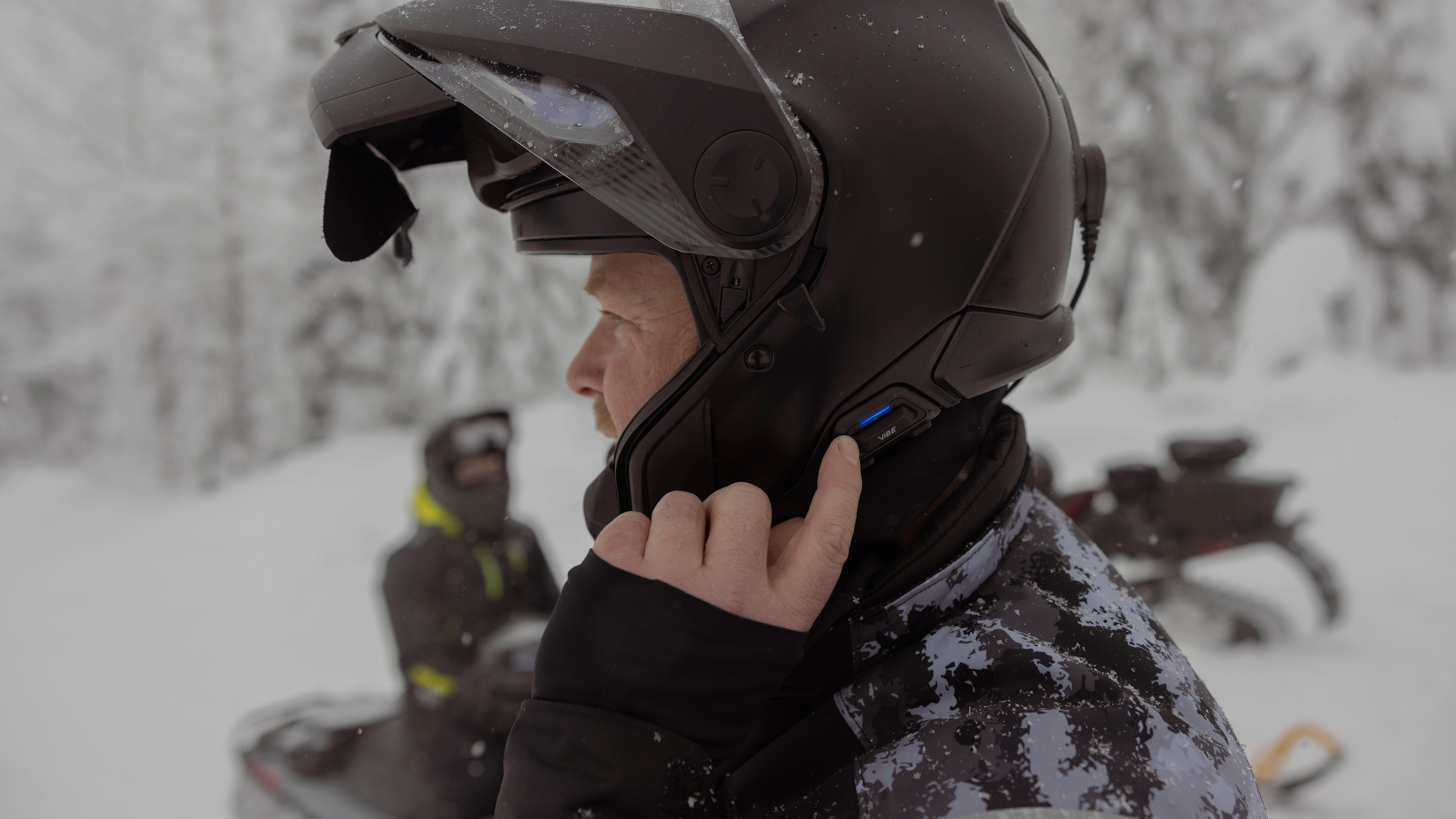 Snowmobile rider putting on the Advex helmet