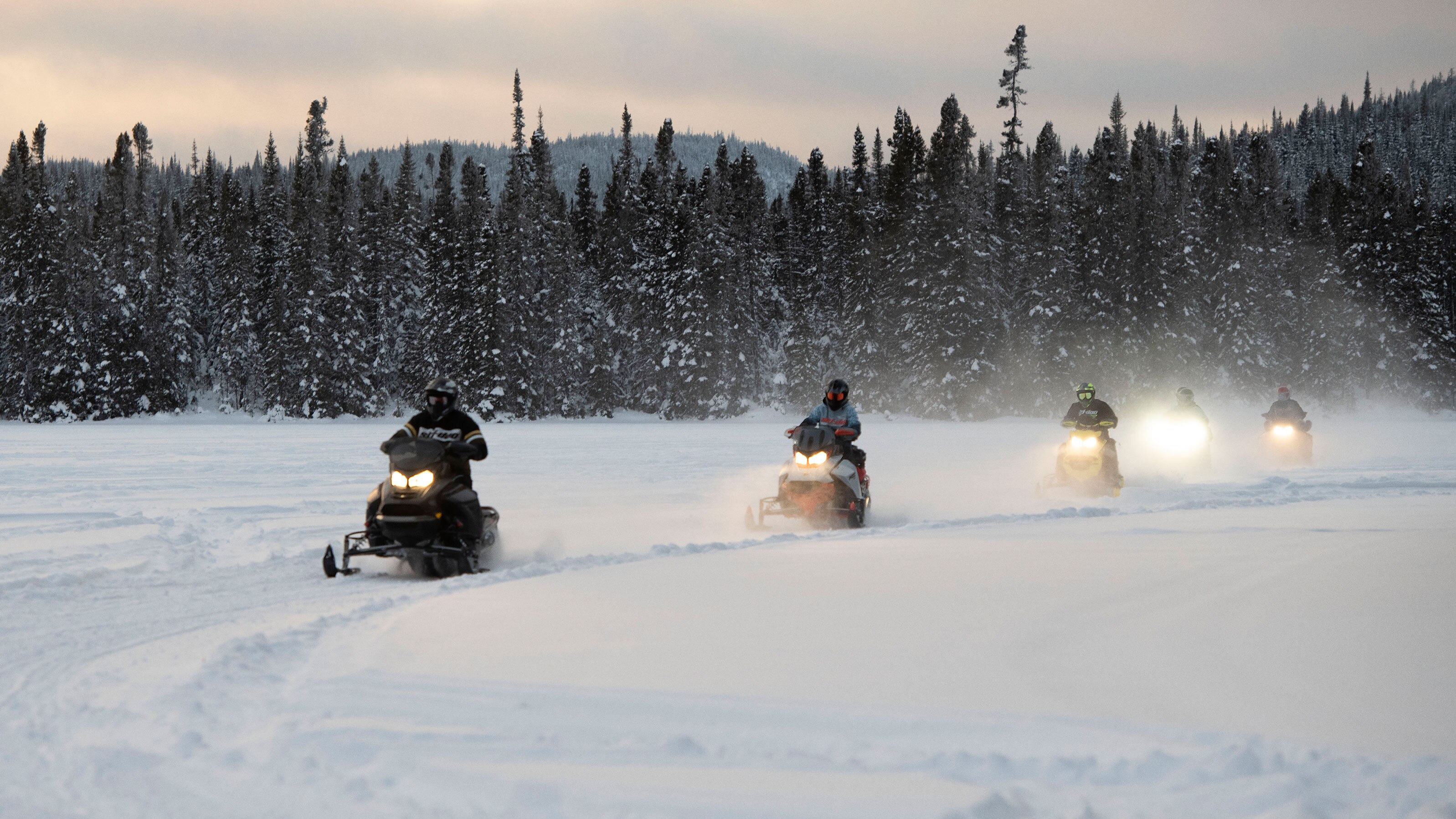 Group of riders snowmobiling at the sunset