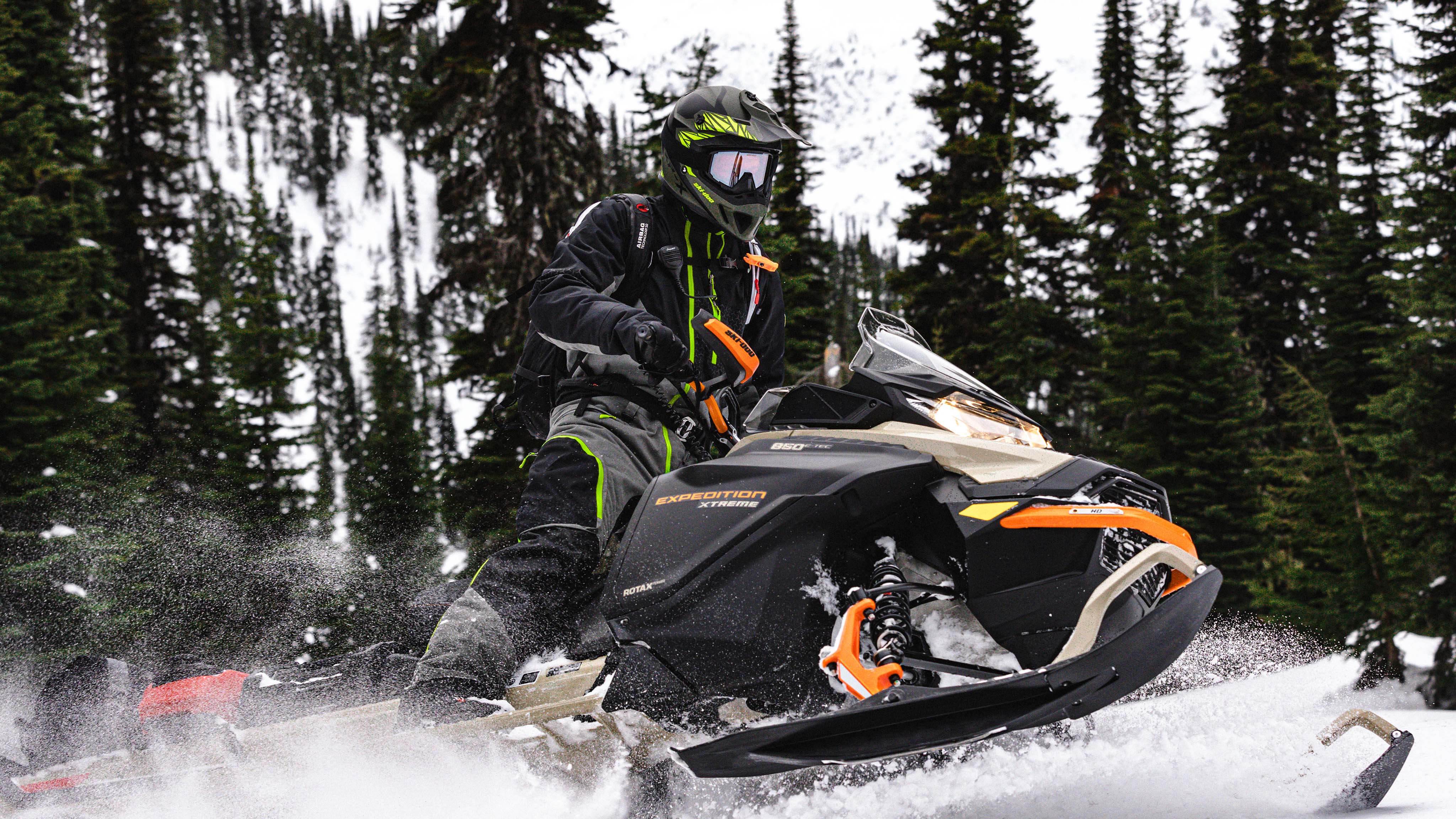Une motoneige Ski-Doo noire et orange sur un sentier forestier
