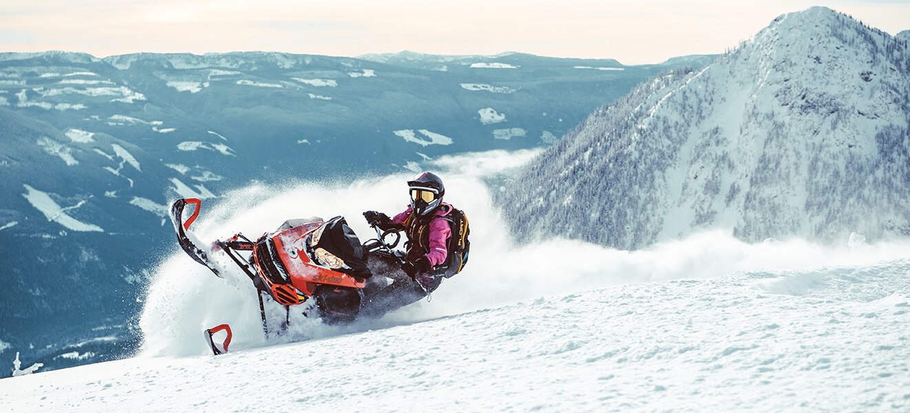 Woman riding a 2021 Ski-Doo Summit SP on a mountain