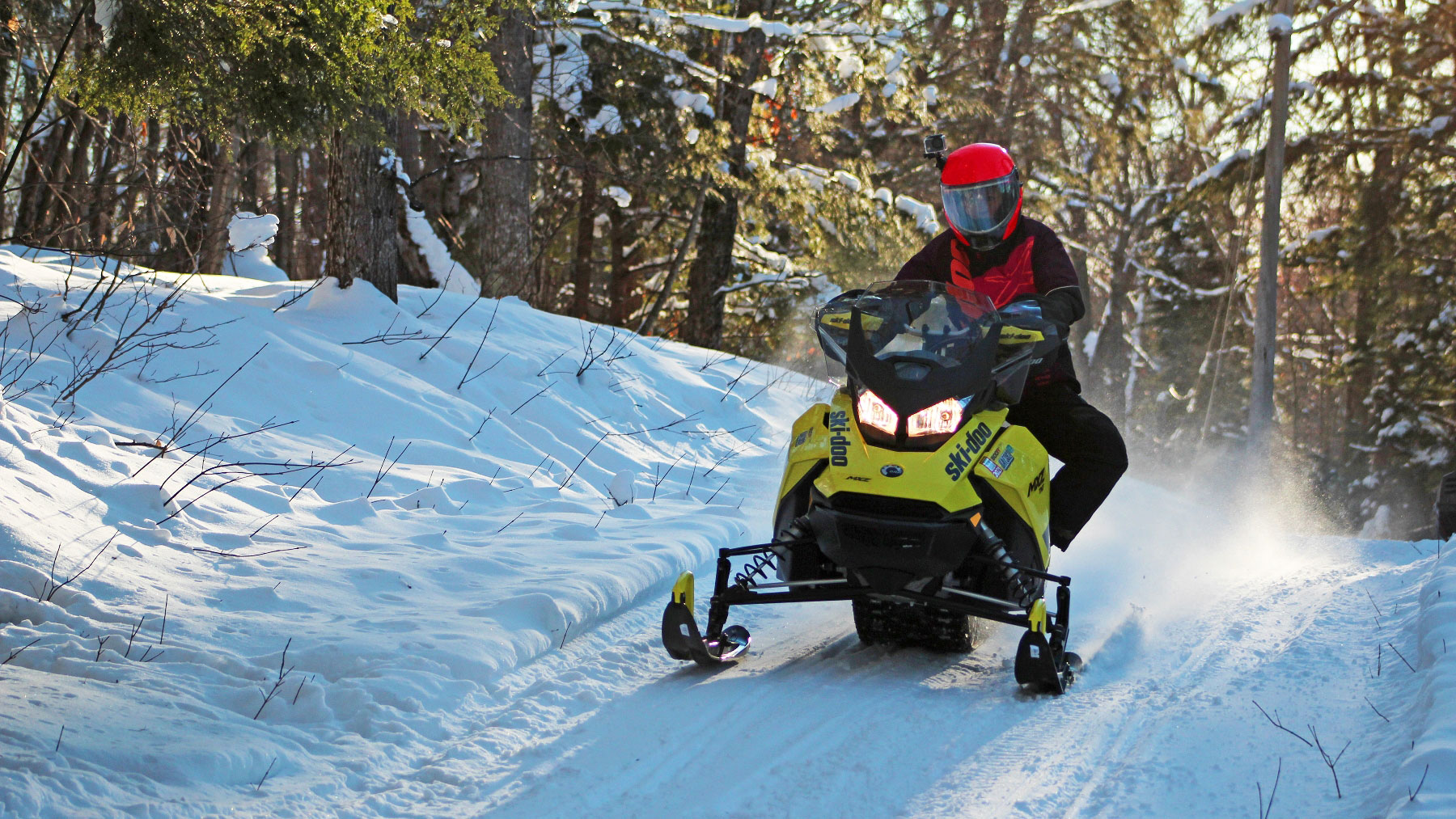 Ski-Doo Ambassador MJ Thompson riding a snowmobile in a trail