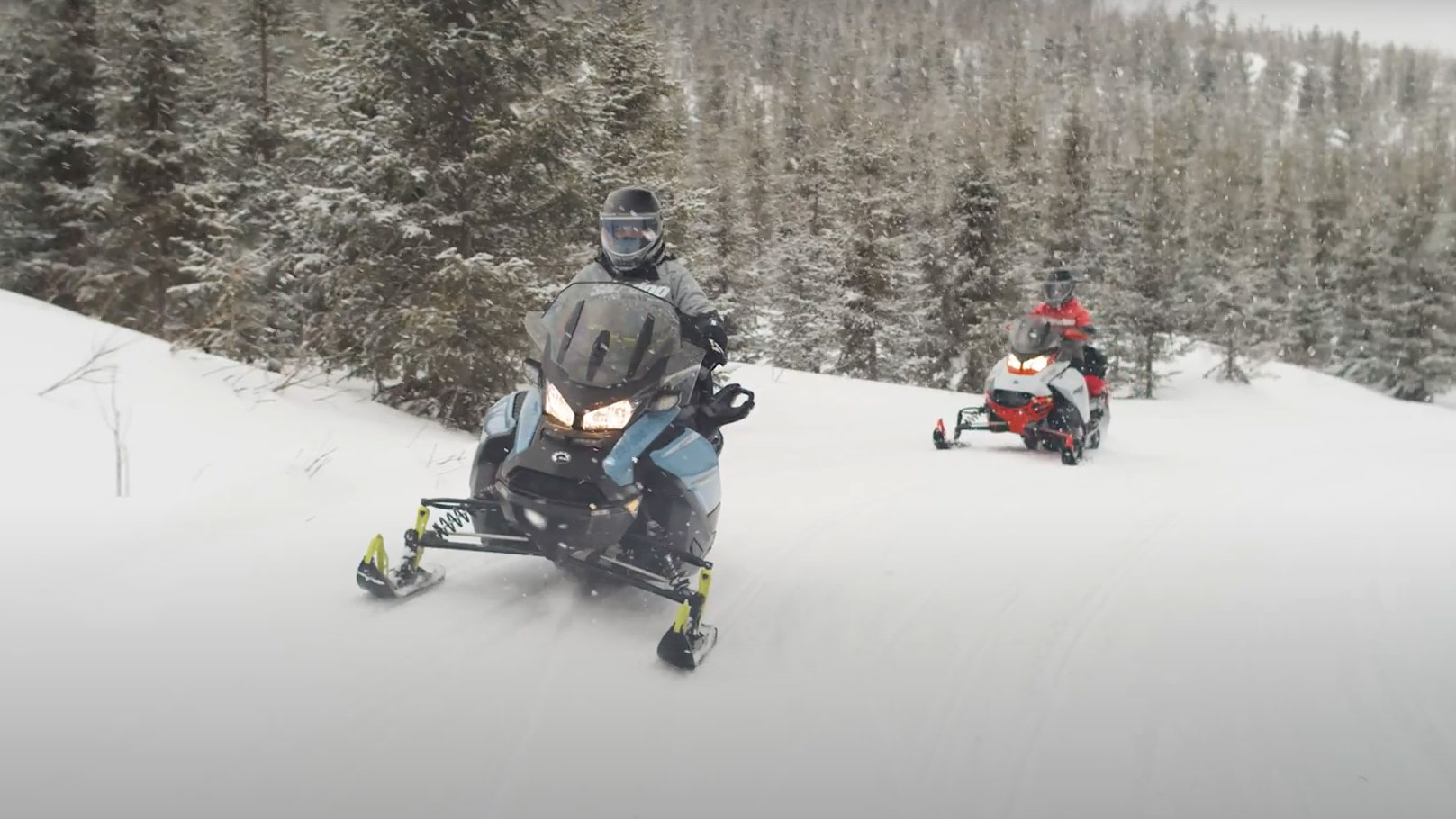 Two women riding Ski-Doo Snowmobiles in trail