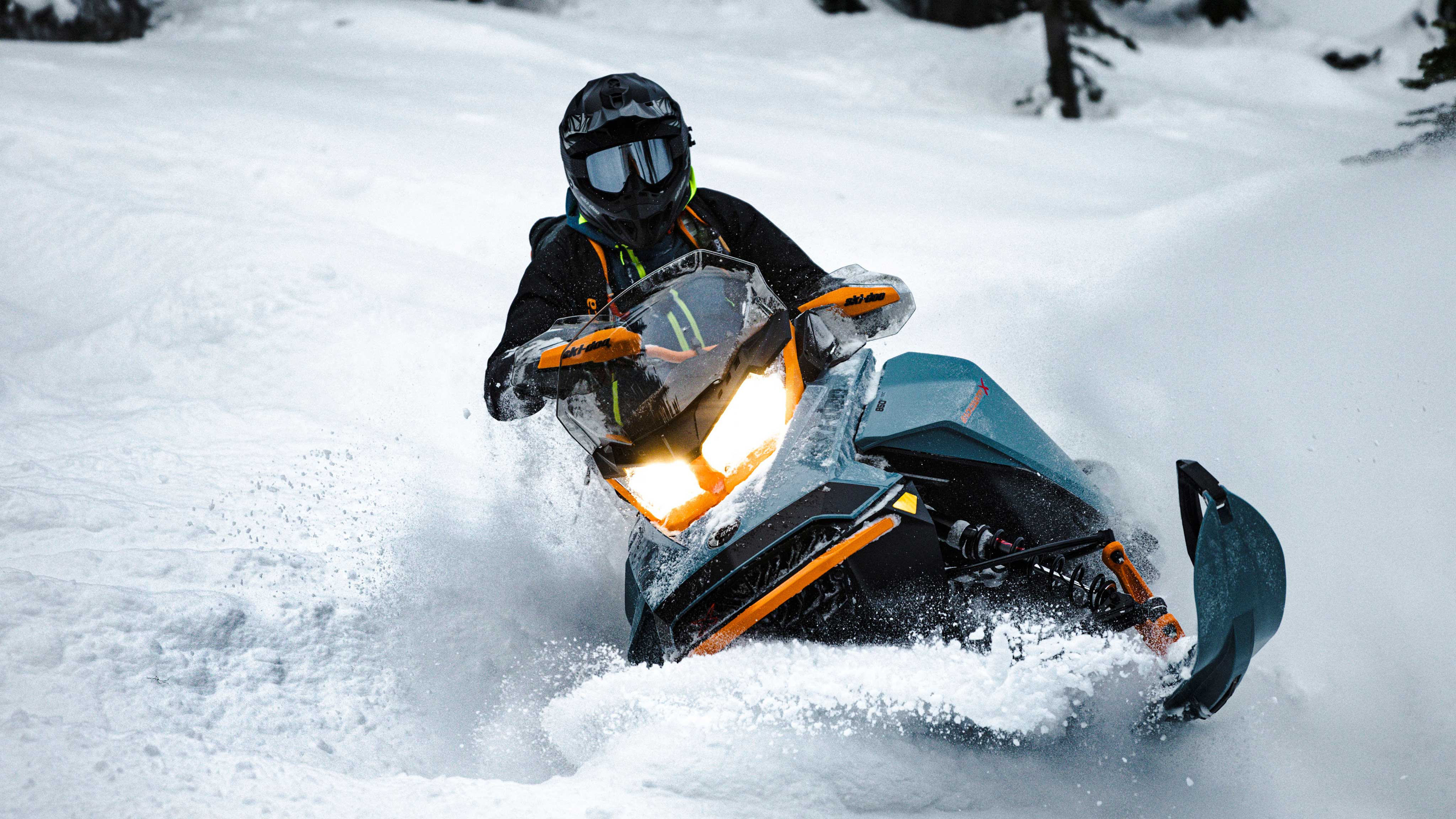Rider riding a blue Ski-Doo Backcountry snowmobile in deep snow