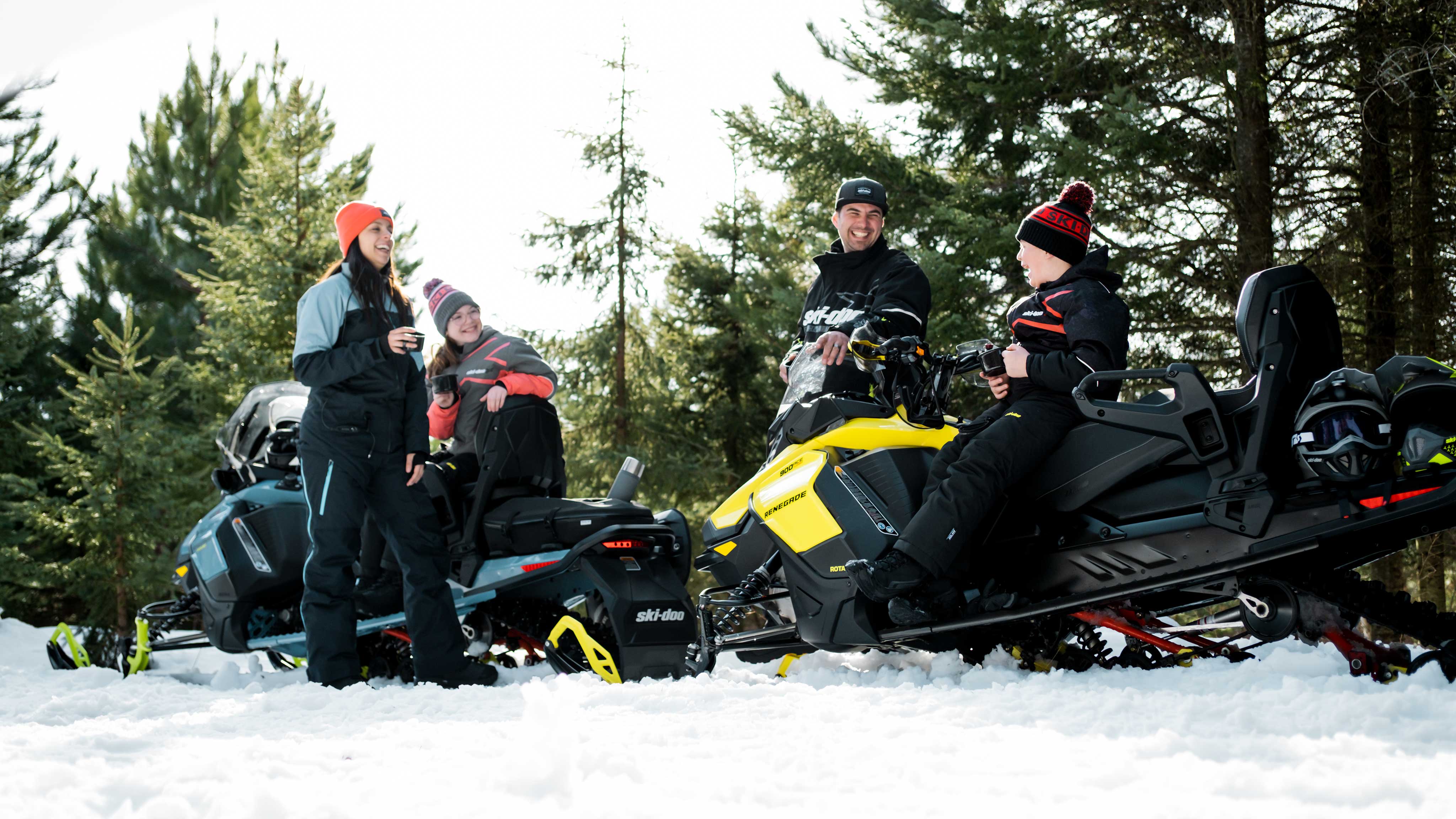 Famille s'amusant à côté de leurs motoneiges Ski-Doo