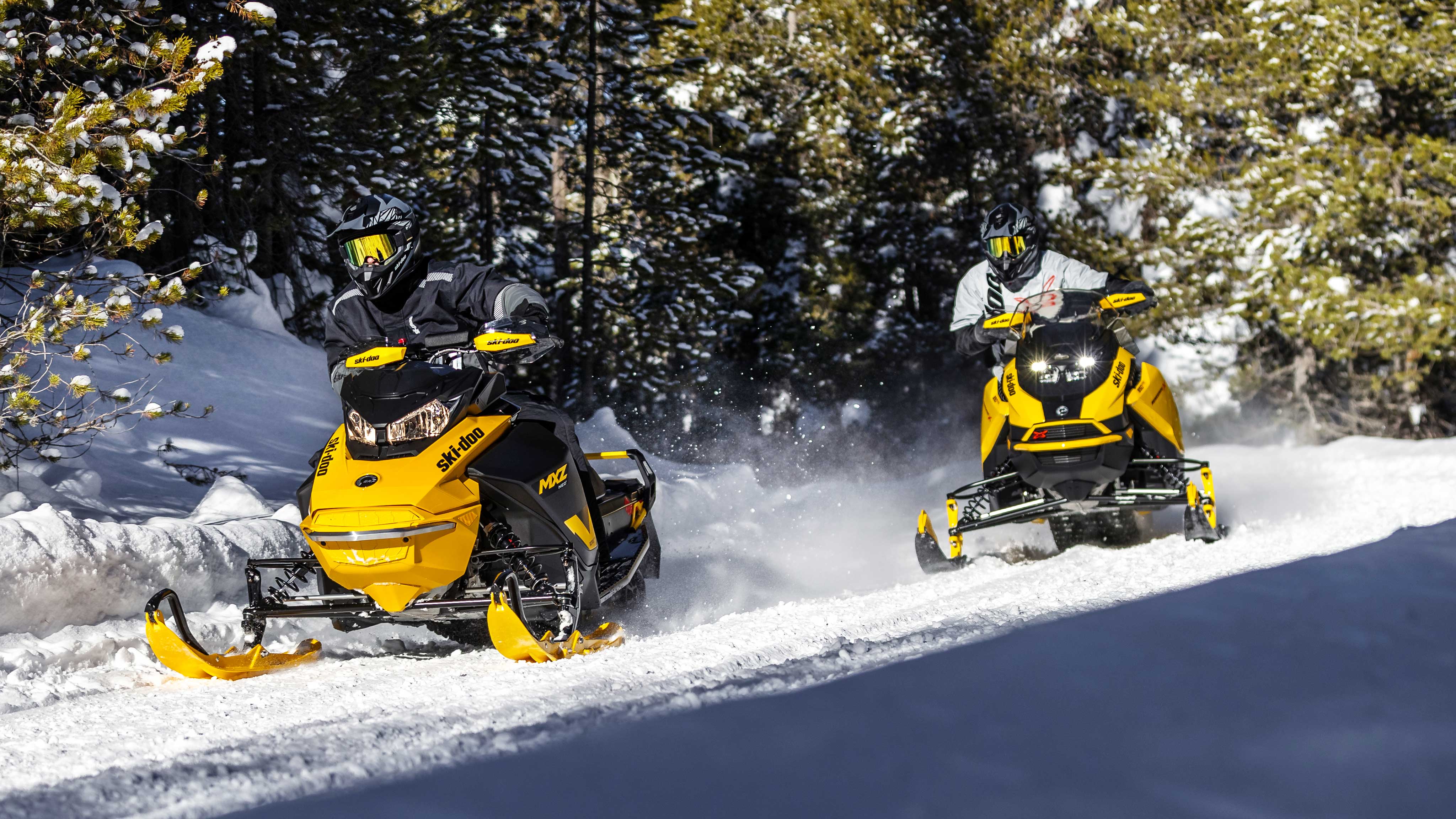 Two man riding Ski-Doo snowmobiles in trail
