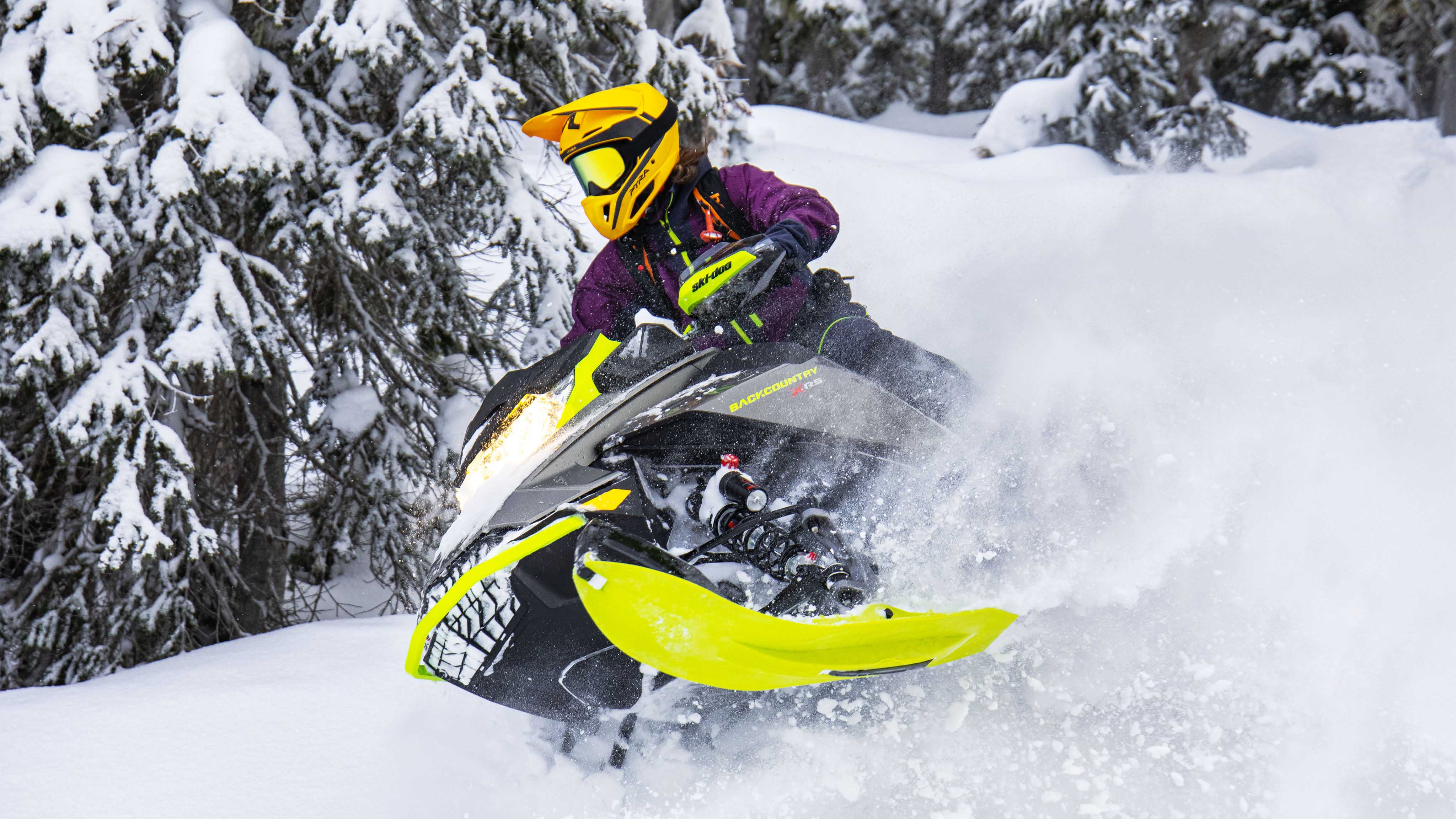 Femme conduisant une motoneige Ski-Doo Backcountry dans la neige profonde