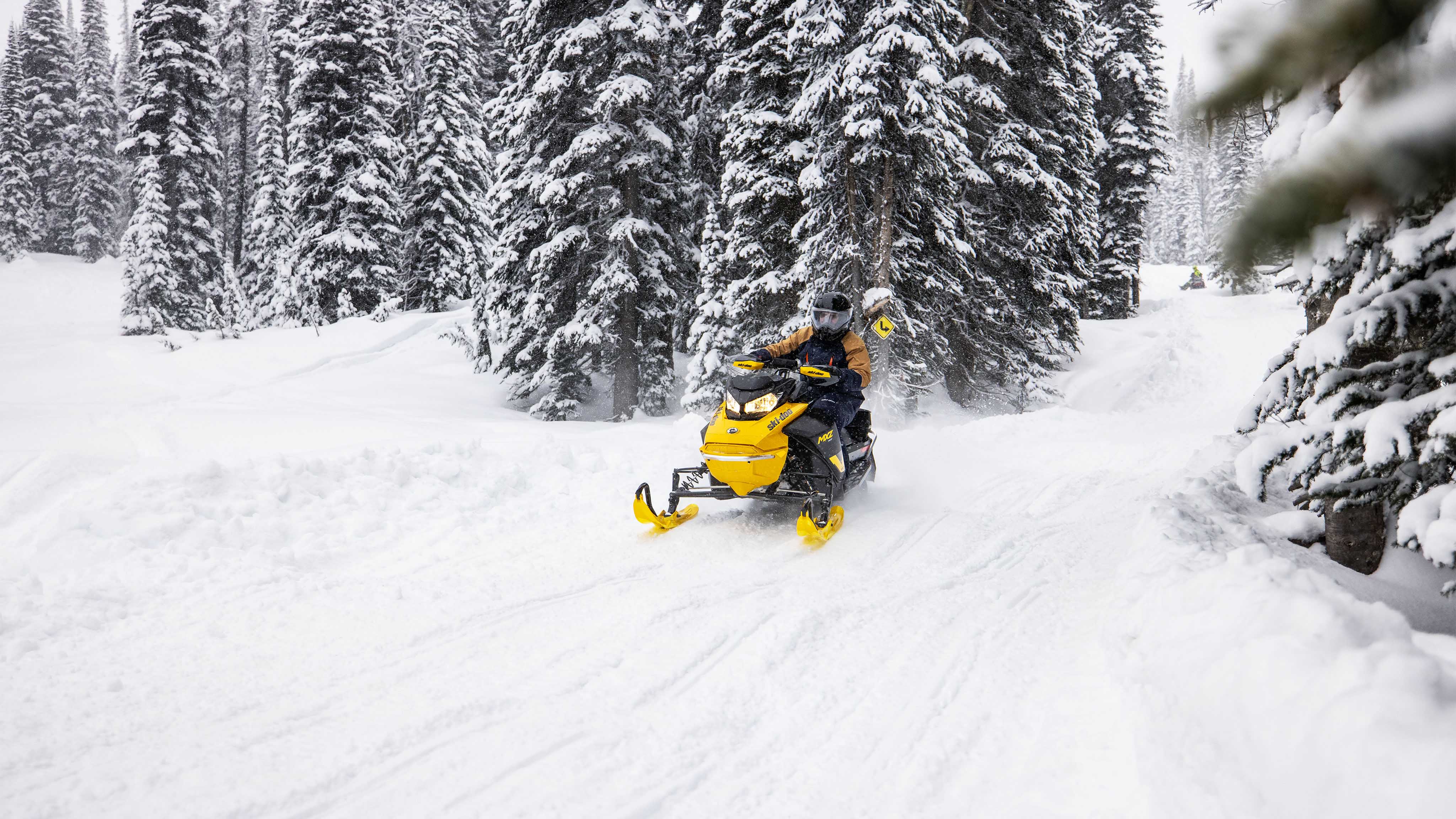 Woman riding a snowmobile trail with the 2023 Ski-Doo MXZ Neo