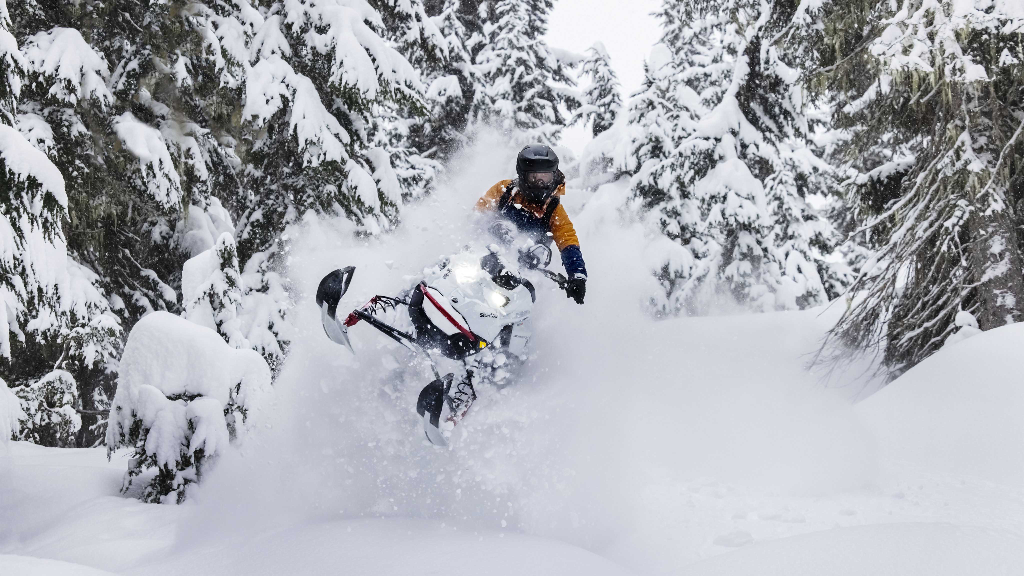 Man jumping in deep snow with a Ski-Doo Summit snowmobile