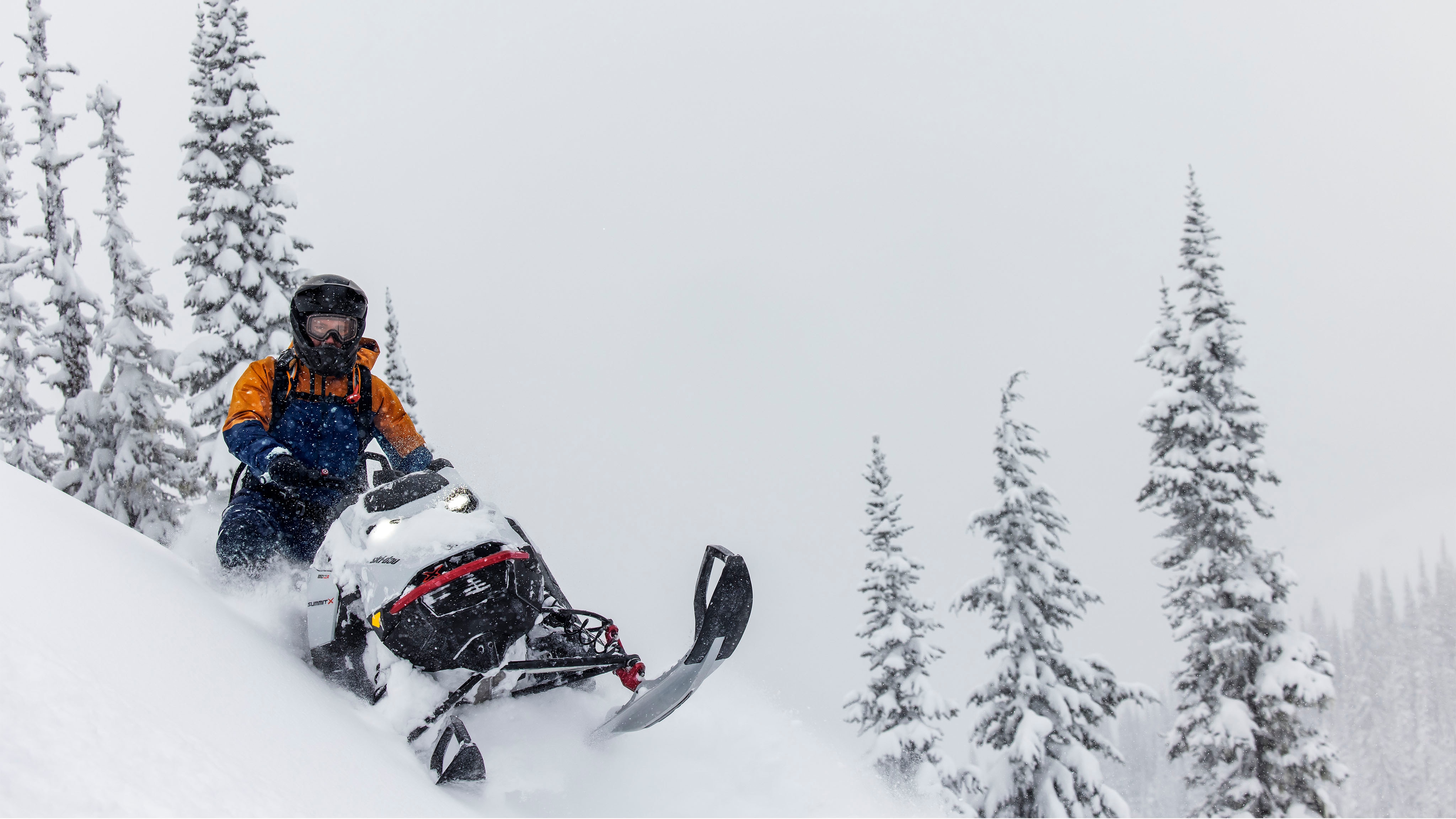 Homme faisant de la motoneige dans la neige profonde avec les vêtements Ski-Doo
