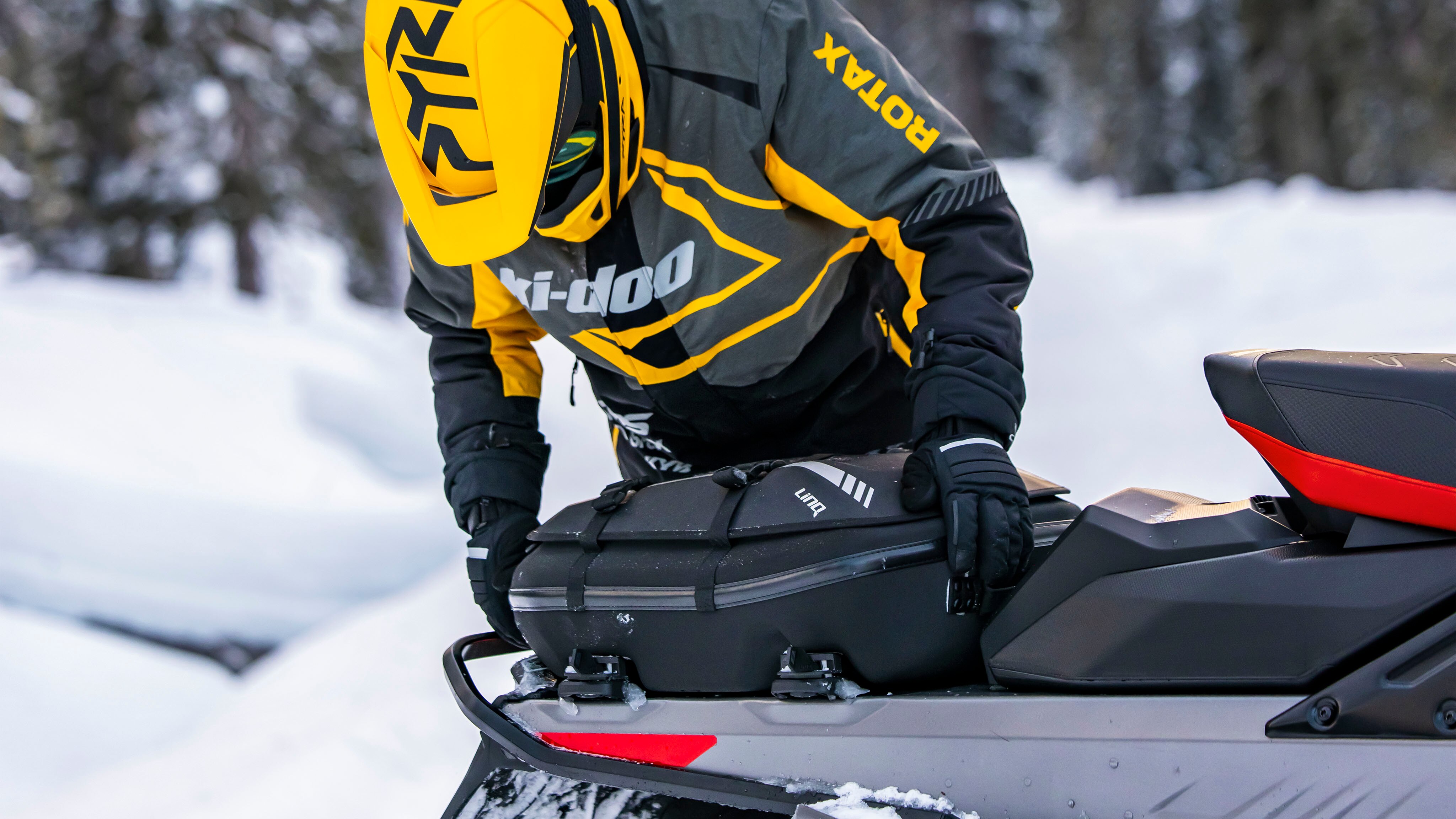 Rider installing a LinQ bag on his Ski-Doo